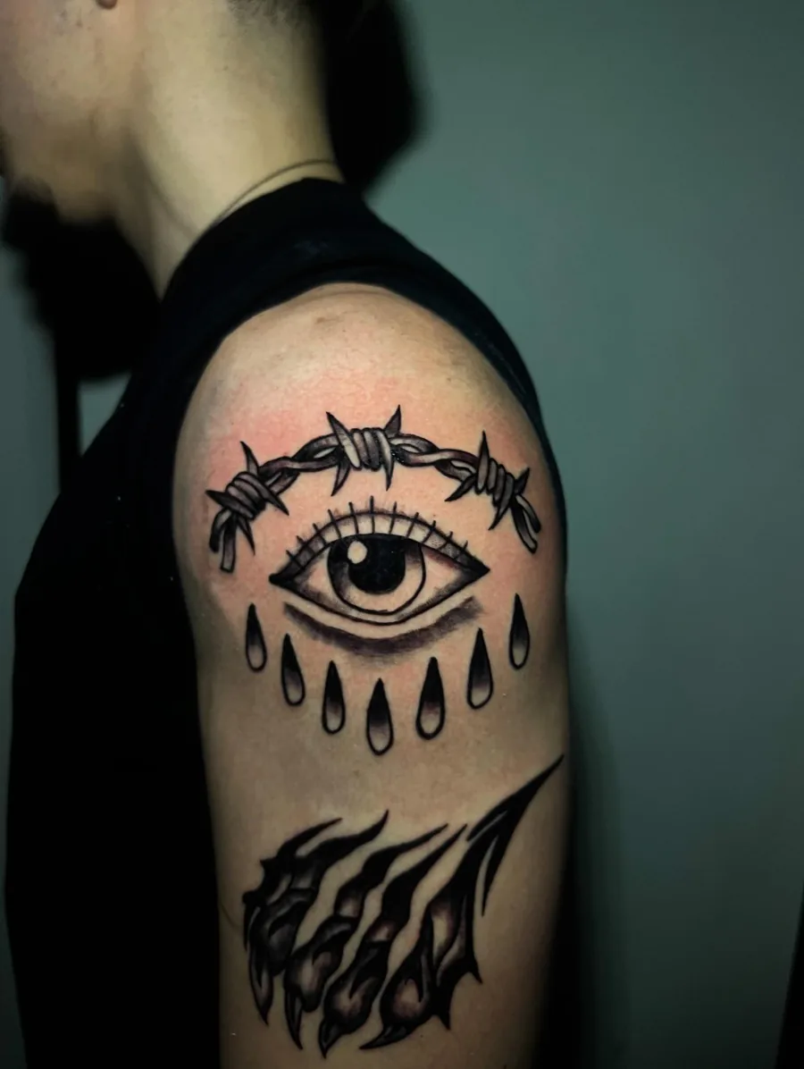 Olho com arame farpado em blackwork no braço